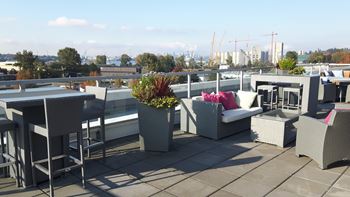 a roof top terrace with tables and chairs and a city in the background